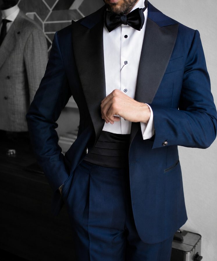 Detail of a navy silk-lapel dinner jacket, hand at the button, House of Lannoy